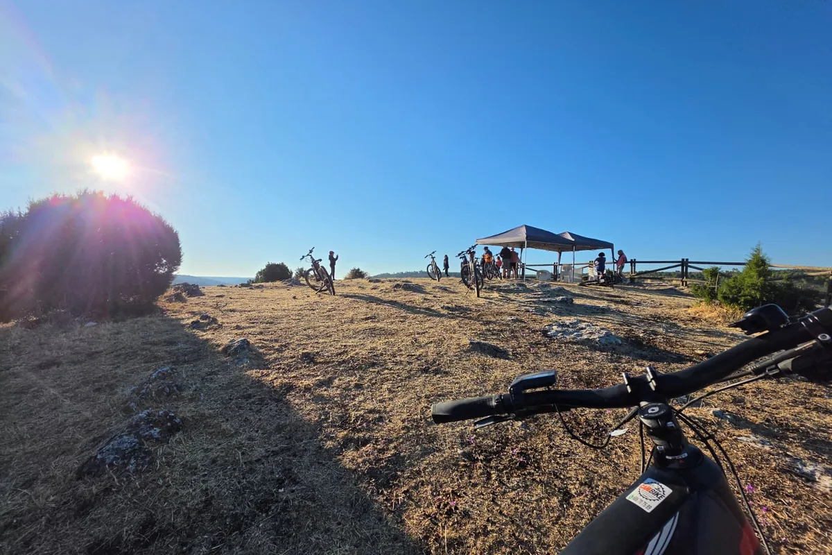 Bicicleta eléctrica en primer plano en un mirador al sol, con el grupo al fondo