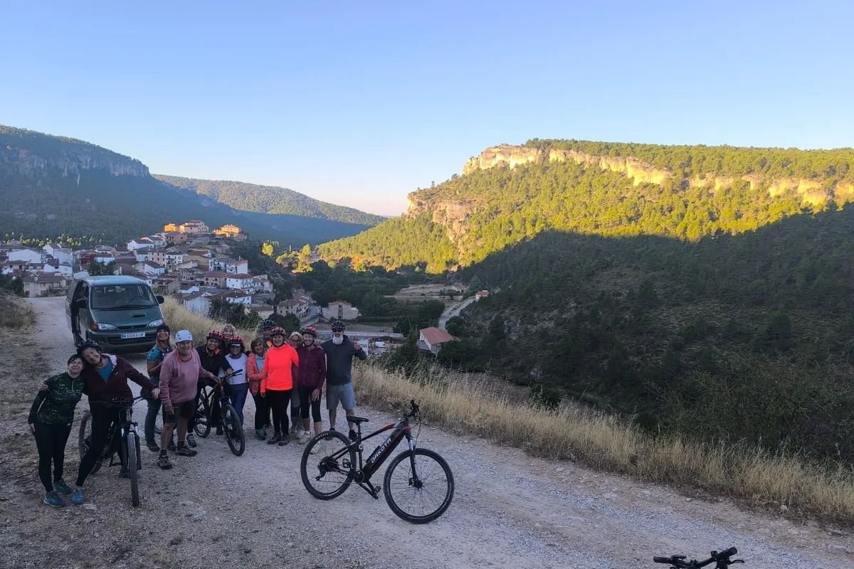 Grupo con bicicletas eléctricas en una pista de tierra sobre el valle, con el pueblo al fondo