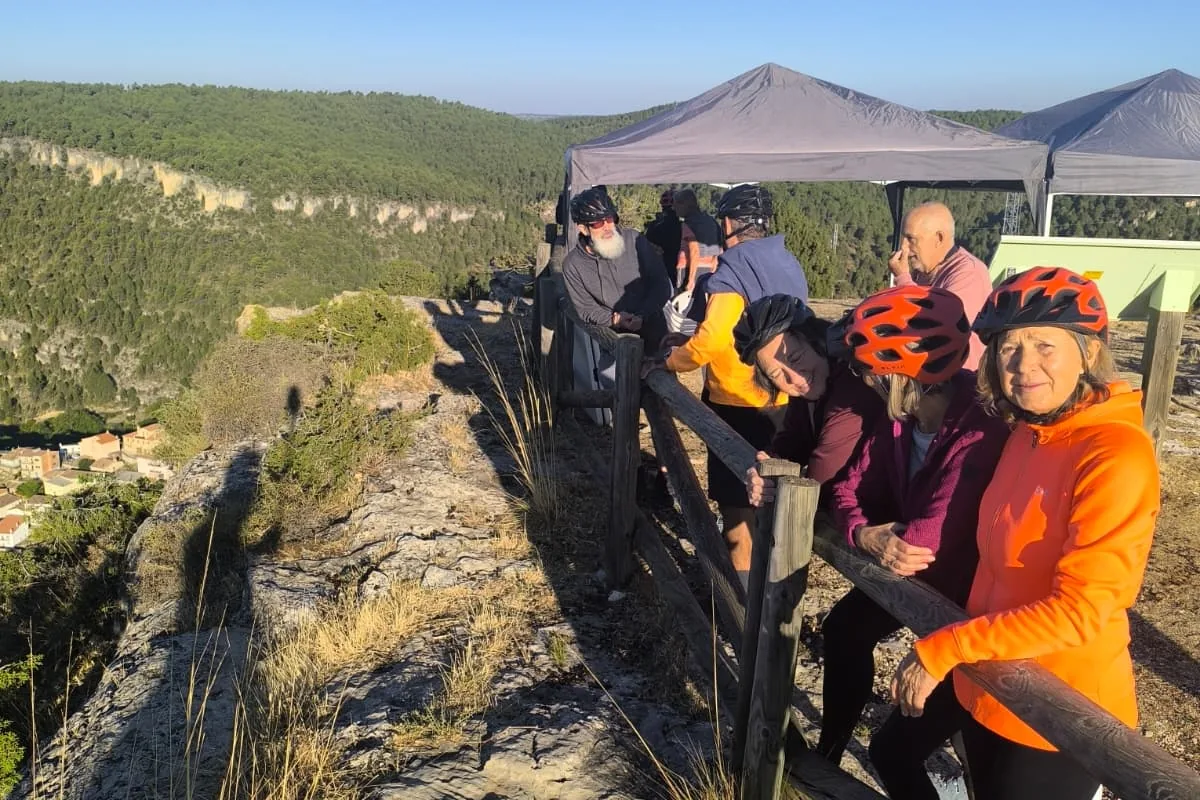 Participantes sonrientes junto a la barandilla del mirador, con la carpa detrás