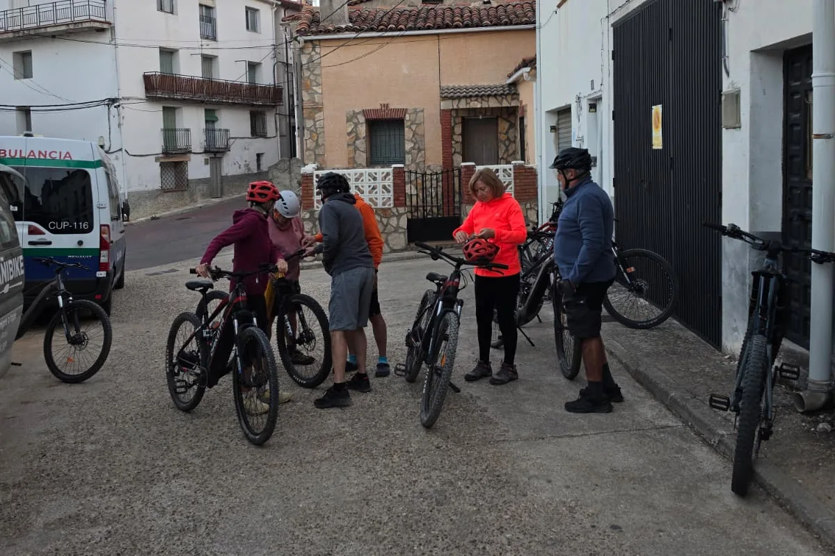 Participantes preparando sus bicicletas eléctricas en una calle del pueblo
